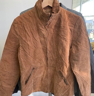 a wrinkled suede jacket on a wooden hanger