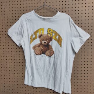 white t-shirt of a brown peg board background, a teddy bear is in the centre, looking a bit beat up, lettering above reads LTD SZN