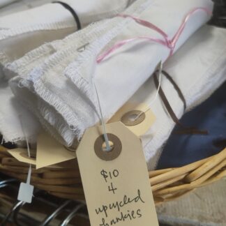 bundles of white handkerchiefs in a basket with a label that describes them as upcycled handkerchiefs - 4 for $10